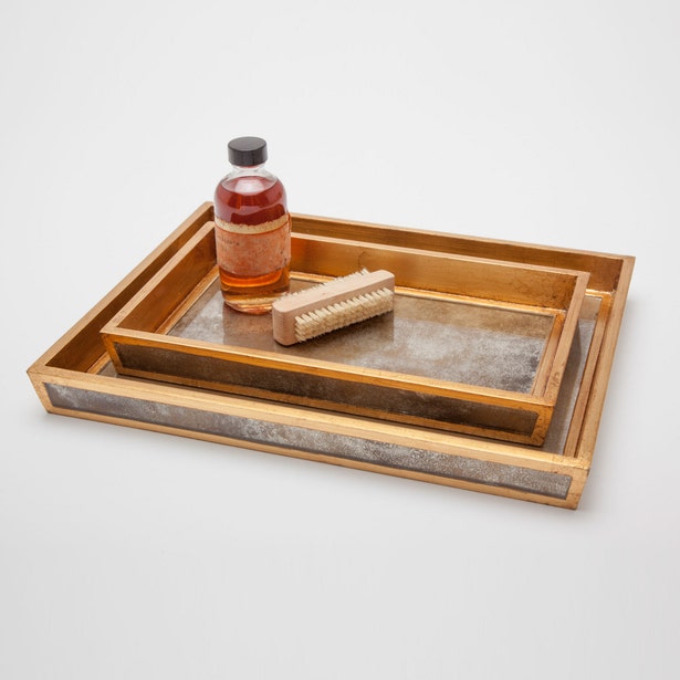 Pigeon & Poodle Atwater trays nested, antiqued mirror base with gold trim, styled with bottle and brush.