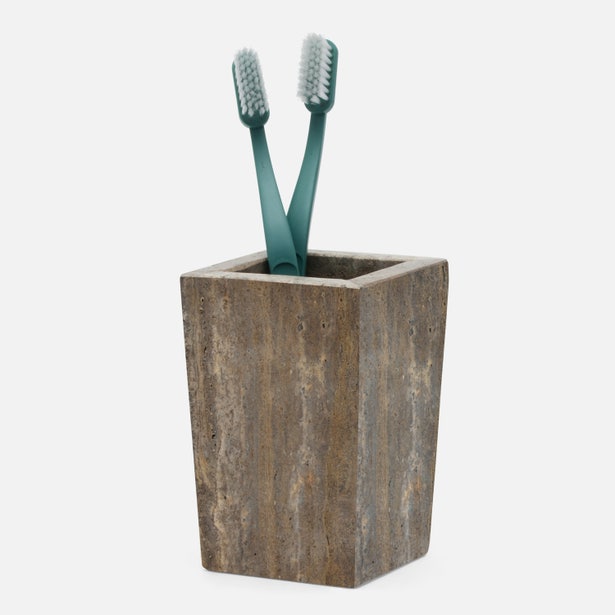 Pigeon & Poodle Bowen brush holder in travertine stone, holding two teal toothbrushes.