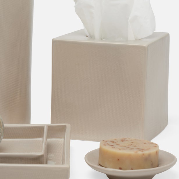 Ivory textured bath accessories set with tissue box, soap dish, and tray in styled scene.