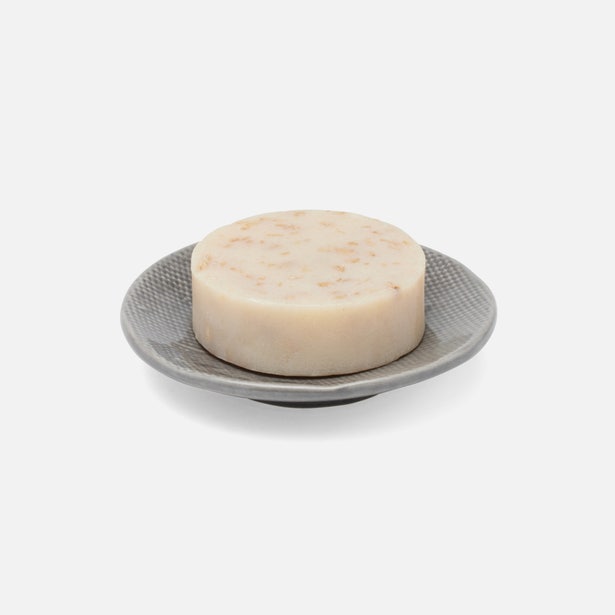 Pigeon & Poodle Cordoba soap dish in grey with textured surface, holding a round ivory bar soap.