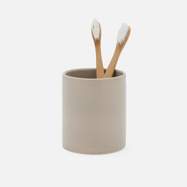 Pigeon & Poodle Cordoba brush holder in taupe with textured surface, holding two bamboo toothbrushes.