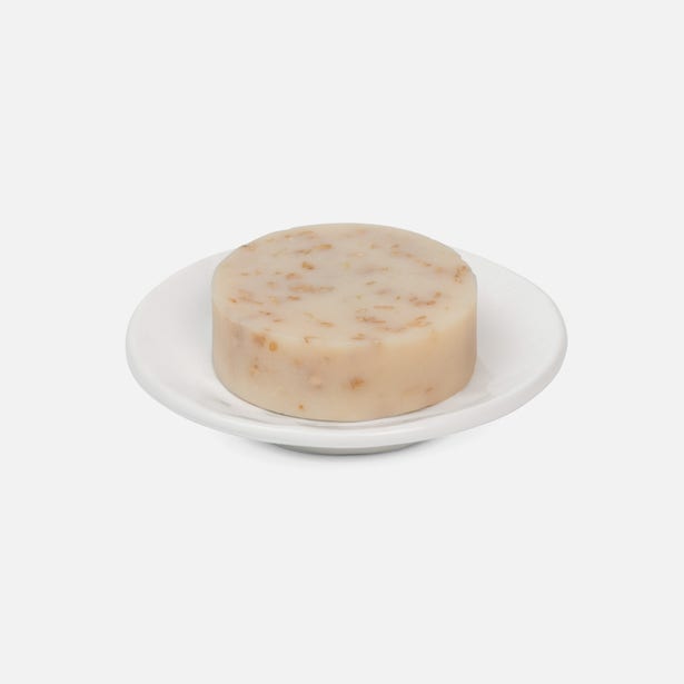 Pigeon & Poodle Cordoba white ceramic soap dish holding a round bar of soap.