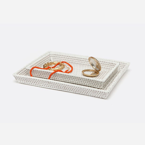 White woven rattan nesting trays styled with gold jewelry and an orange beaded bracelet.