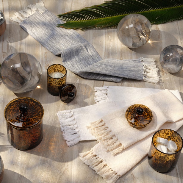 Styled flatlay with fringed linen towels, crystal spheres, and tortoiseshell Pigeon & Poodle Darby bath canisters.