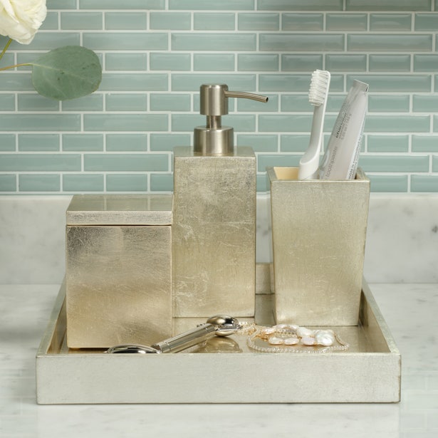 Champagne textured soap pump styled with matching bath accessories on marble countertop.