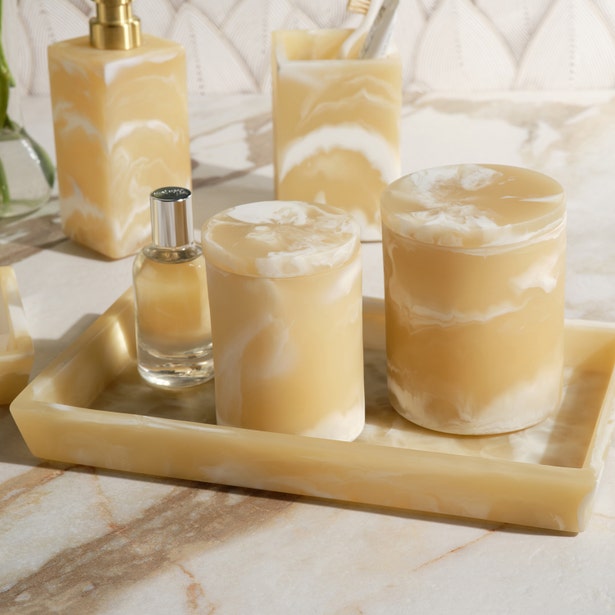 Honey onyx marble-effect resin tray styled with matching bath accessories on a marble surface.
