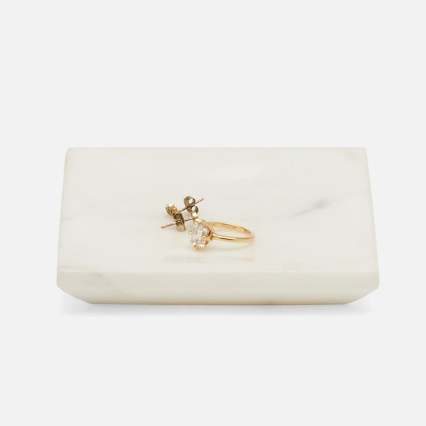 White marble Pigeon & Poodle Elyria tray holding a gold ring and stud earrings, angled view.