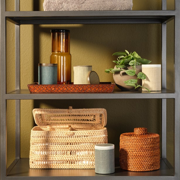 Amber glass carafe on styled bathroom shelf with woven accessories and greenery.