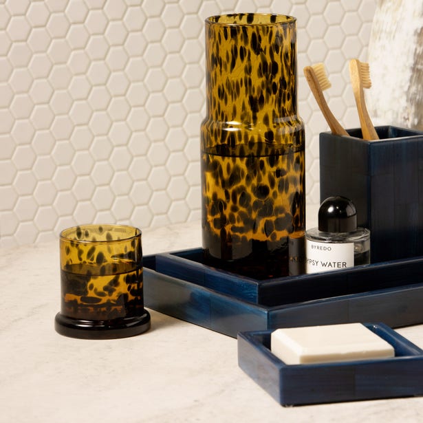 Close-up of Pigeon & Poodle Faro tortoiseshell glass carafe and tumbler on navy tray.