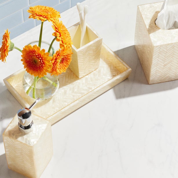 Ivory herringbone brush holder on marble surface with matching bathroom accessories.