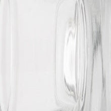 Close-up of clear glass carafe showing curved handle and subtle ribbed texture.