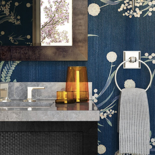 Amber glass carafe styled on marble vanity beside matching tumbler in navy floral bathroom.