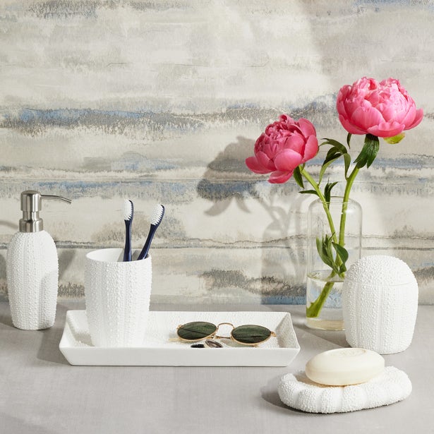 White textured ceramic bath accessories set styled with pink peonies on a marble surface.