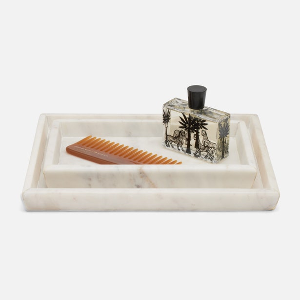 Two white marble Kavala nesting trays styled with a comb and perfume bottle on a white background.