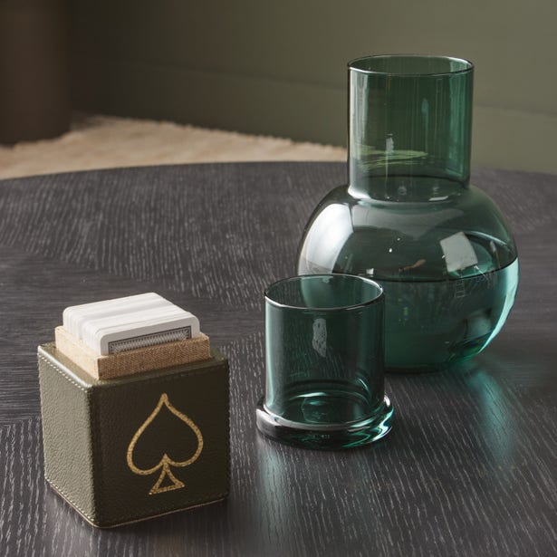 Teal glass carafe and tumbler set styled with a card holder on a dark wood surface.