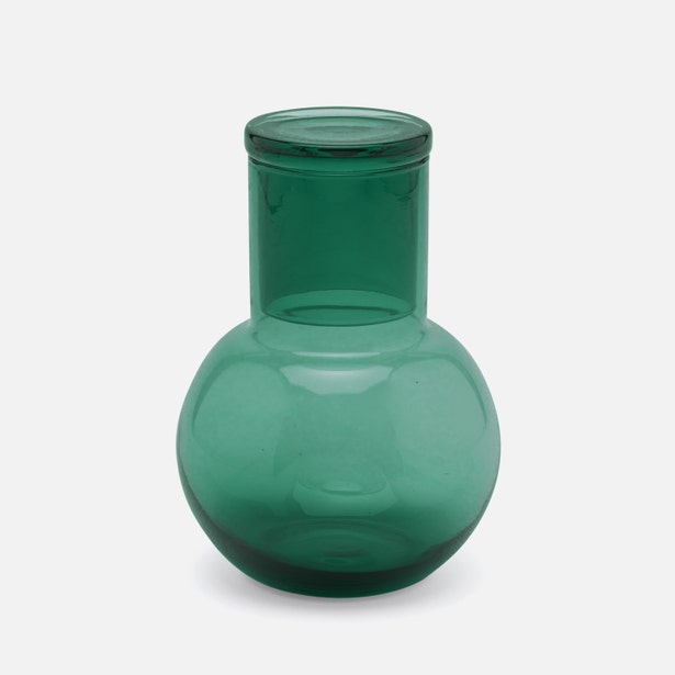 Emerald green glass carafe with round bulbous base and cylindrical neck, against white background.