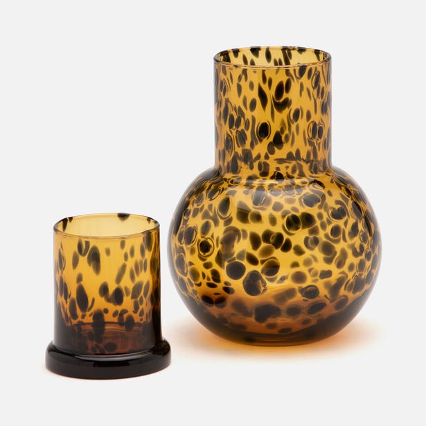 Amber tortoiseshell glass carafe and tumbler set with black spot pattern.