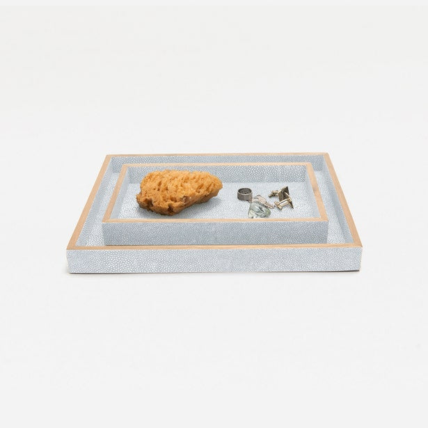 Grey shagreen-textured nesting trays with gold trim, styled with a natural sponge and small accessories.