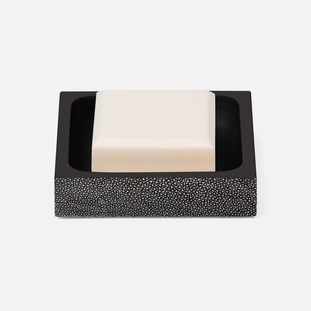 Black shagreen-textured soap dish holding an ivory bar of soap, angled view.