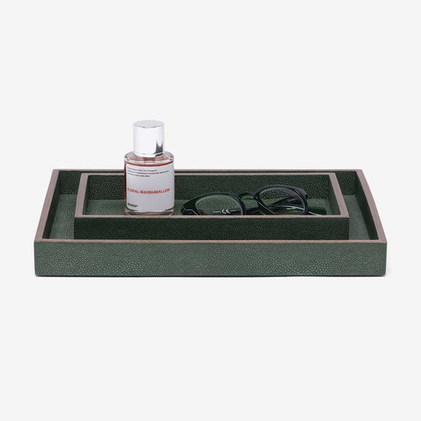 Forest green shagreen-texture nesting trays styled with perfume bottle and folded sunglasses.