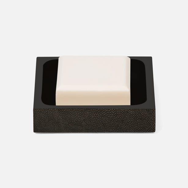 Black shagreen-textured soap dish holding an ivory bar of soap, square profile.