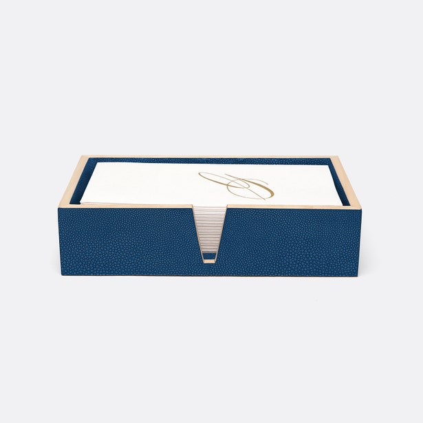 Navy blue shagreen-textured tray holding white hand towels with gold monogram detail.