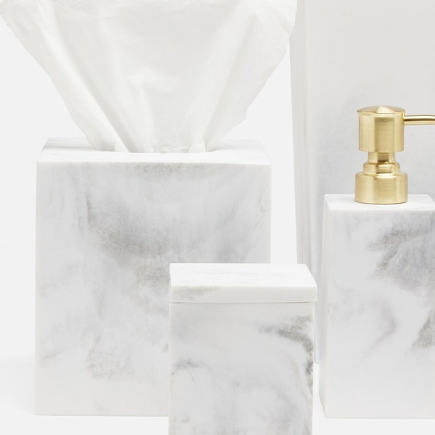 White and grey marble-effect soap dish beside tissue box cover and soap dispenser with gold pump.
