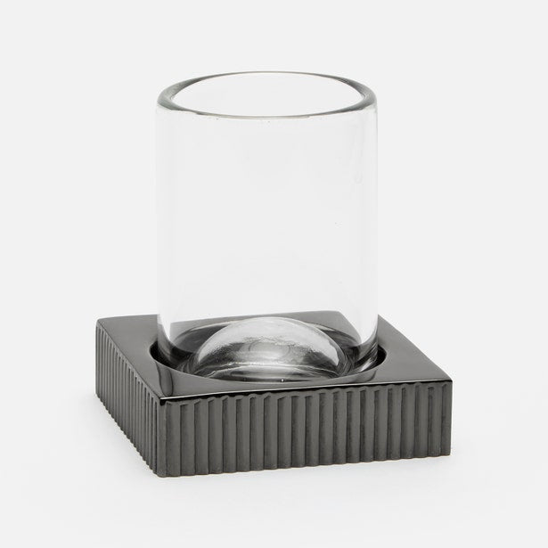 Clear glass tumbler on ribbed dark gunmetal square base, angled side view.
