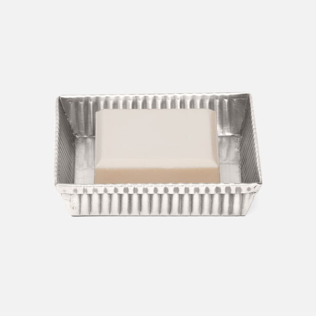 Silver ridged rectangular soap dish holding an ivory bar of soap, angled view.