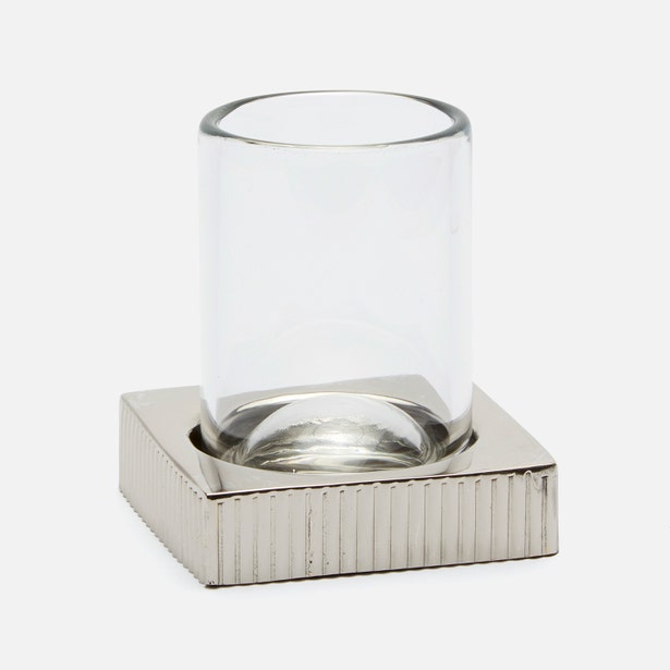 Clear glass tumbler on ribbed square polished nickel base, angled view.