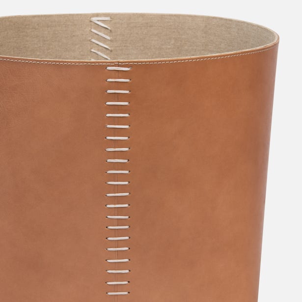 Close-up of tan leather basket with white saddle stitch seam detail and natural interior lining.