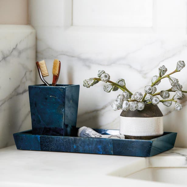 Midnight blue crackle-glaze tray styled on marble surface with matching tumbler and small vase.