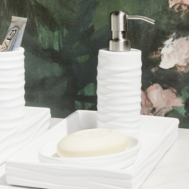 White Solin soap dish and pump dispenser set with rippled texture, styled on bathroom counter.