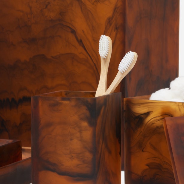Two bamboo toothbrushes in a Pigeon & Poodle Tavira tortoiseshell resin bath canister, warm amber tones.