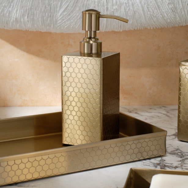 Gold honeycomb-embossed soap dispenser and tray set styled on marble surface.