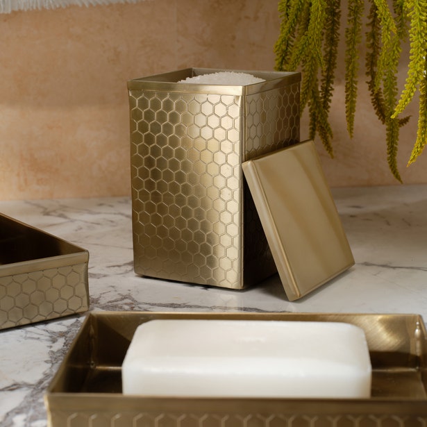 Temara brush holder in antique brass with honeycomb texture, lid ajar on marble surface.