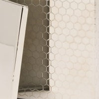 White hexagonal tile wall with a silver metallic brush holder corner detail.
