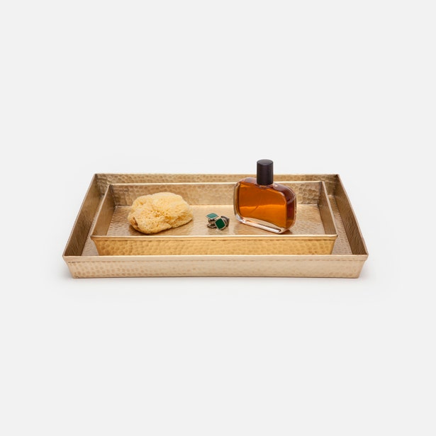 Pigeon & Poodle Verum hammered gold tray styled with sponge, perfume bottle, and earrings.