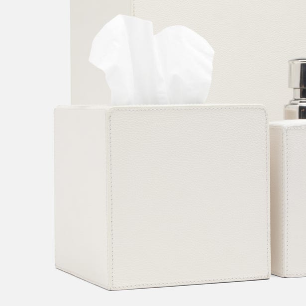 Ivory pebbled faux leather tissue box cover with white tissue, soap pump partially visible.