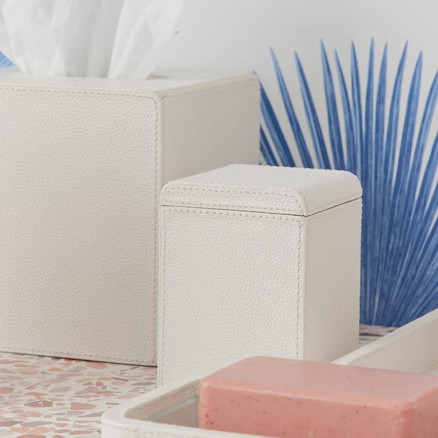 Ivory pebbled faux leather bathroom accessories styled with blue palm leaf and pink soap bar.