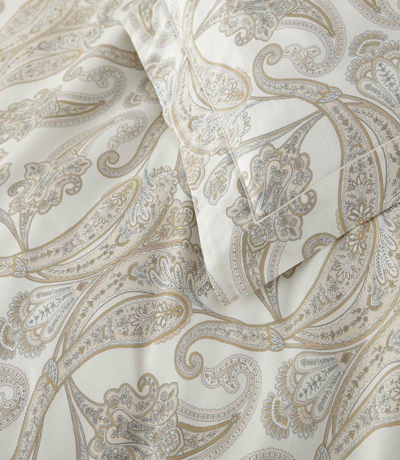Close-up of champagne and grey paisley print on ivory cotton duvet cover.