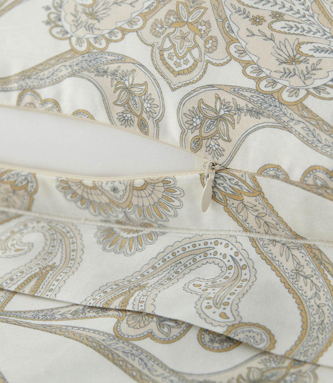 Close-up of Peacock Alley Paisley Pearl duvet cover zipper closure, ivory cotton with gold and slate paisley print.