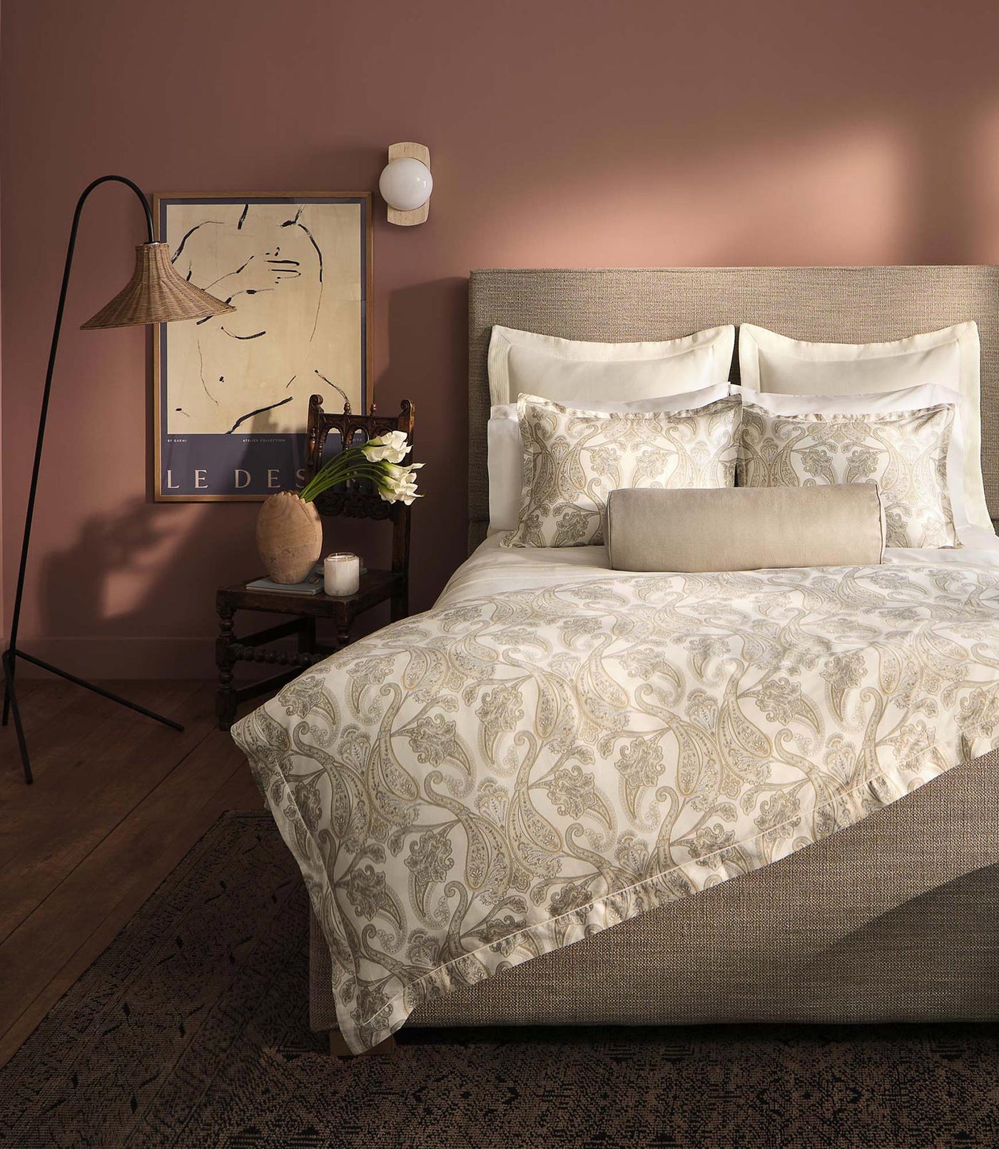 Champagne paisley duvet styled on a neutral upholstered bed against a dusty rose wall.