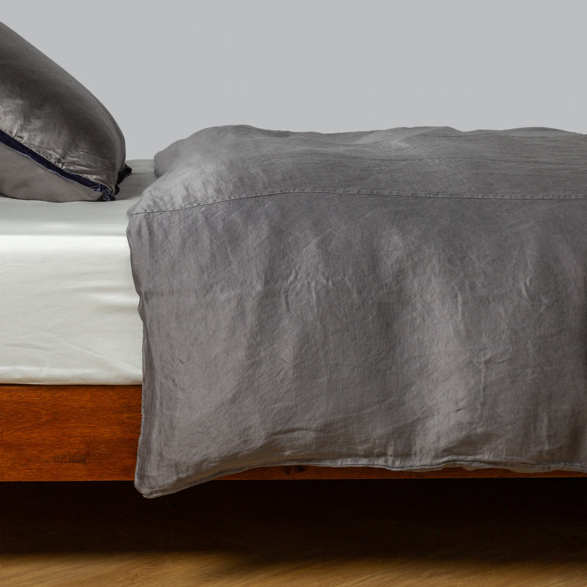 Paloma duvet cover in French Lavender draped over bed, showing relaxed linen texture and subtle sheen.