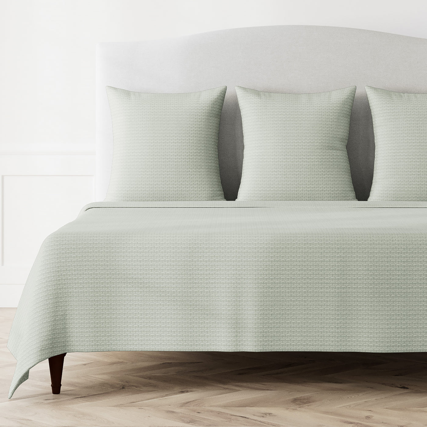 Ann Gish Pavilion coverlet in sage, styled on bed with matching shams, subtle woven pattern.