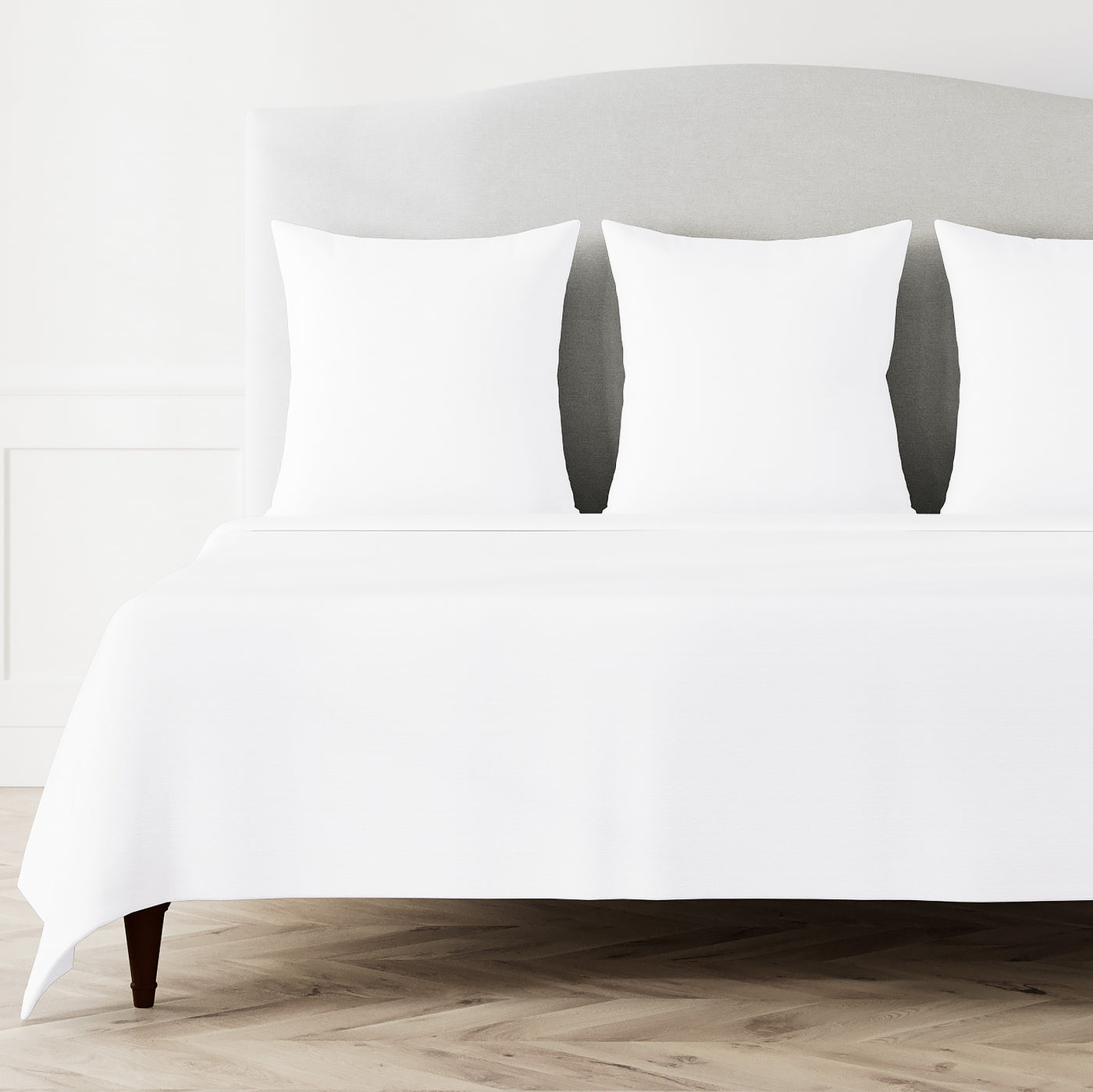 White Ann Gish Pavilion coverlet draped over a styled bed with matching pillow shams.
