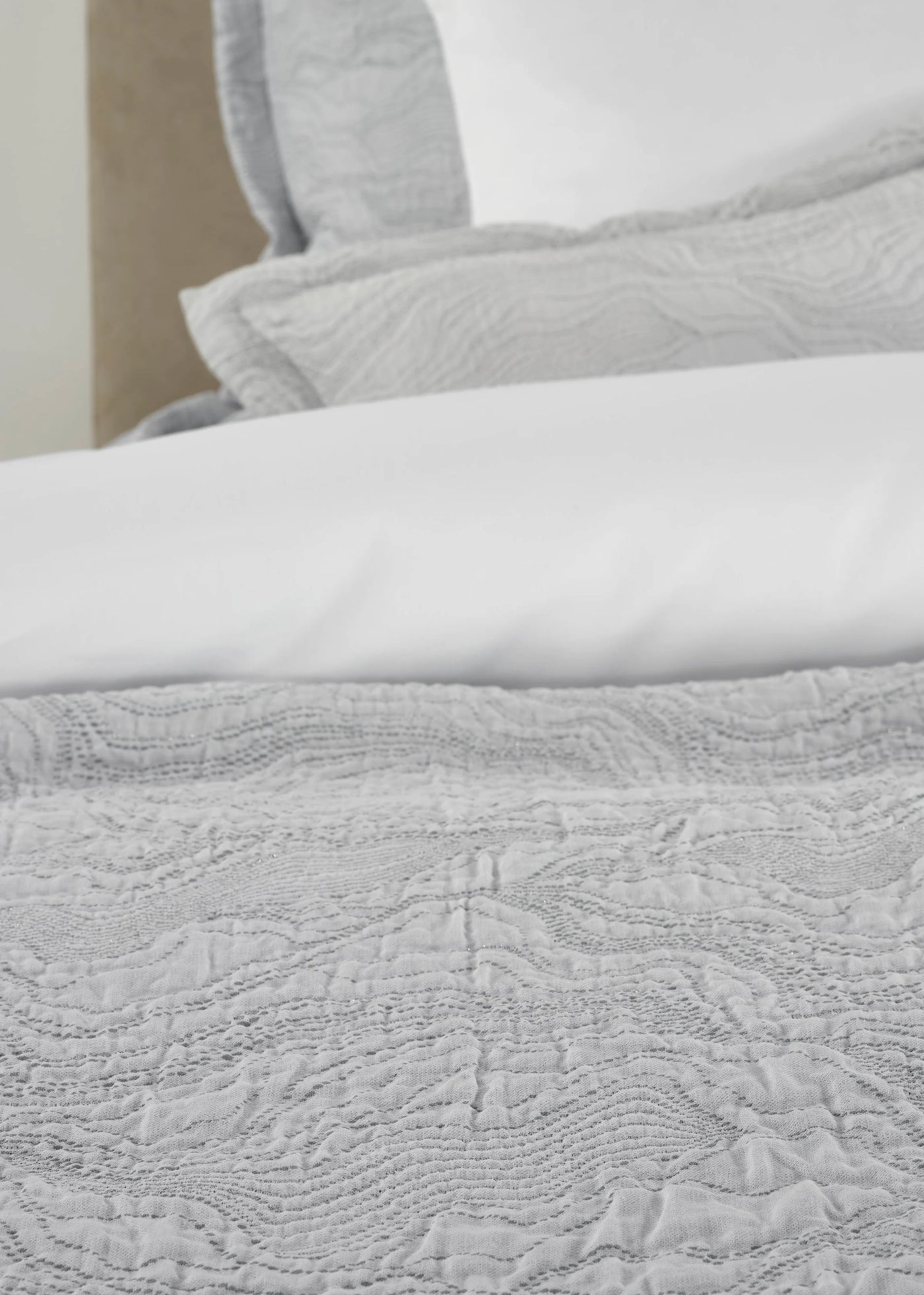 Close-up of Celso de Lemos Perle coverlet in silver with quilted wave pattern.