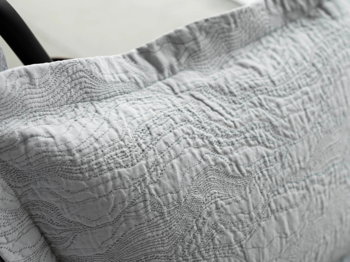 Close-up of Celso de Lemos Perle coverlet in silver-grey with wave-textured quilting detail.
