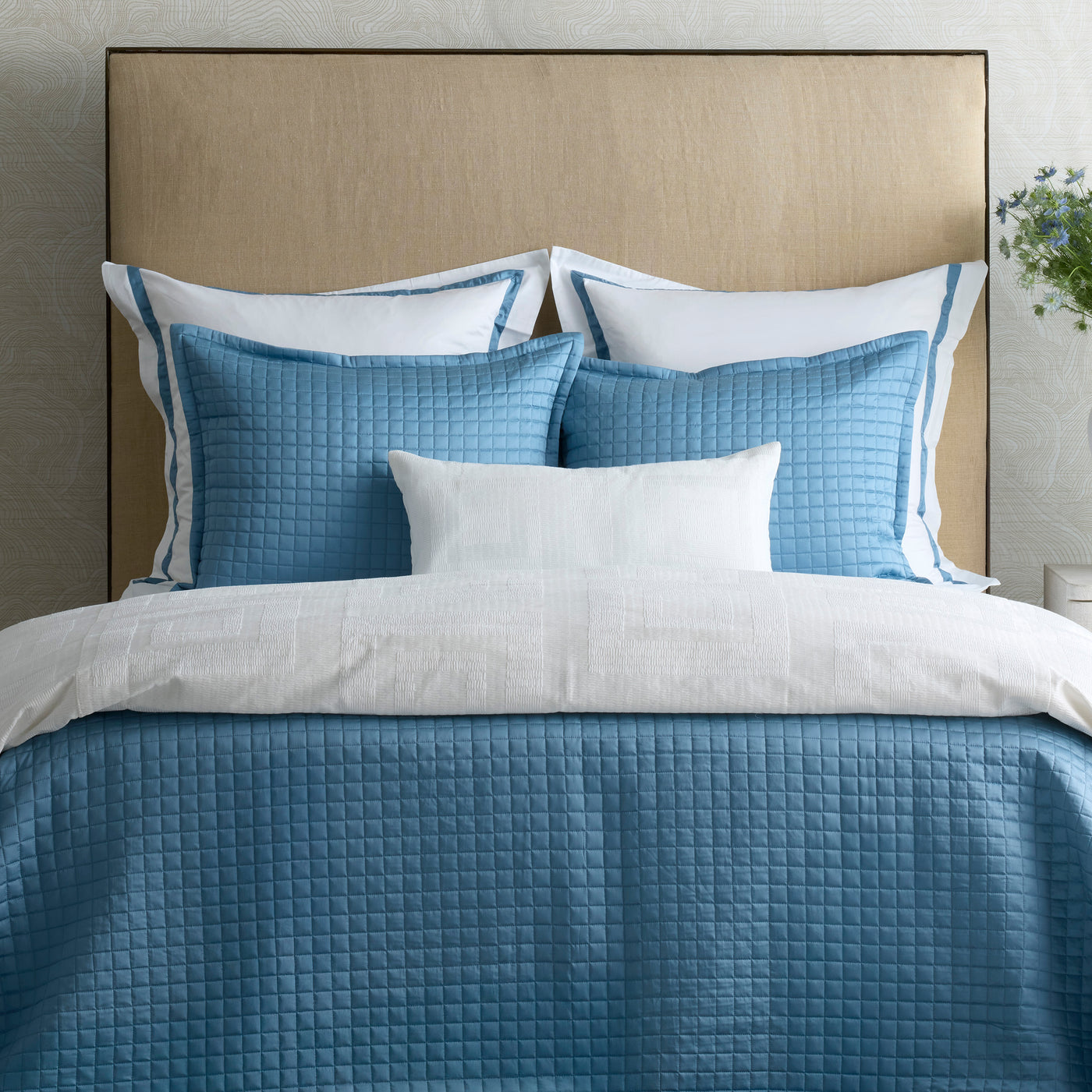 Cornflower blue quilted Piastrella duvet cover styled on bed with matching shams.