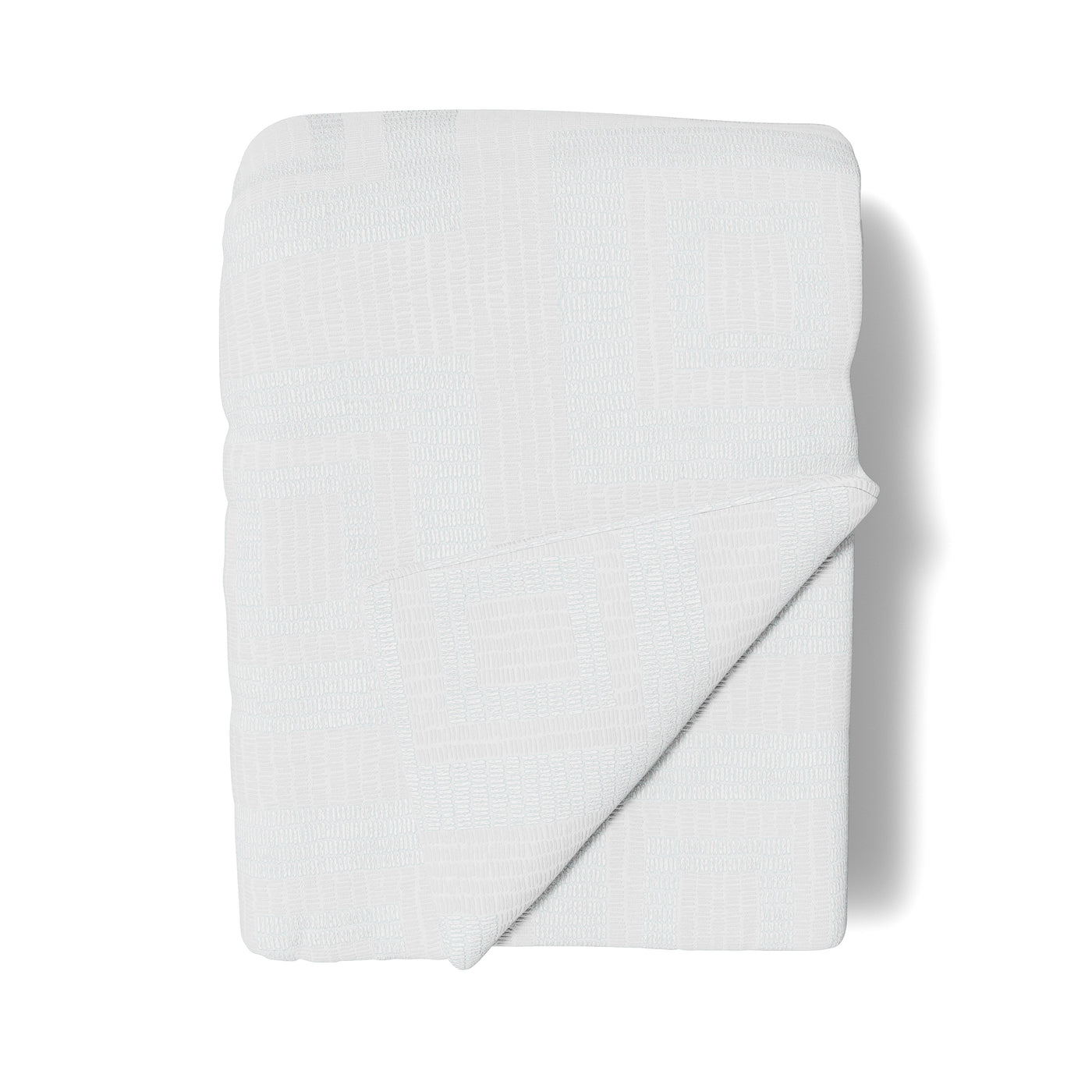 Folded white throw with textured tile-pattern weave, corner turned back to reveal texture.